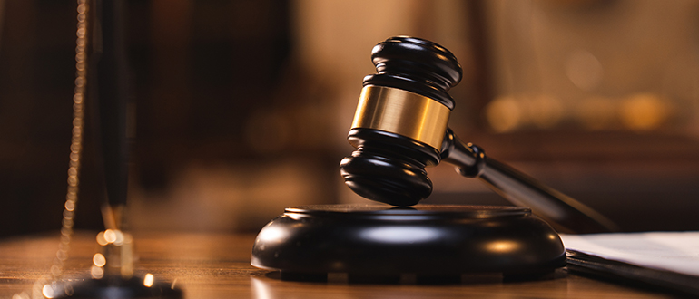 Judge gavel on the table with blurry books in the background